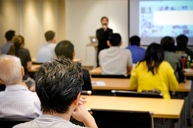 学员们正在参加课堂培训，讲师正在通过投影屏幕进行演示。
