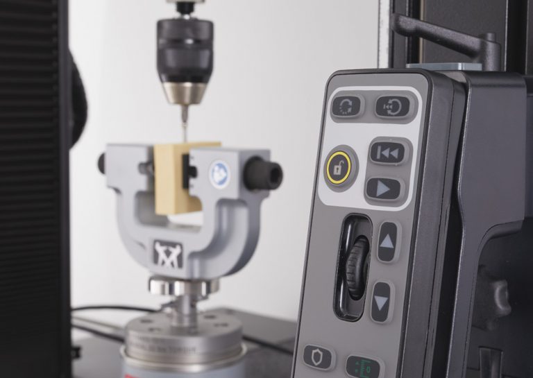 Instron 6800 Series handset with rotation controls for the Torsion Add-On, with a bone screw test in the background